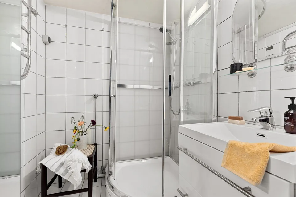 Badet på Marienlyst før totalrenoveringen med hvite fliser og dusjkabinett